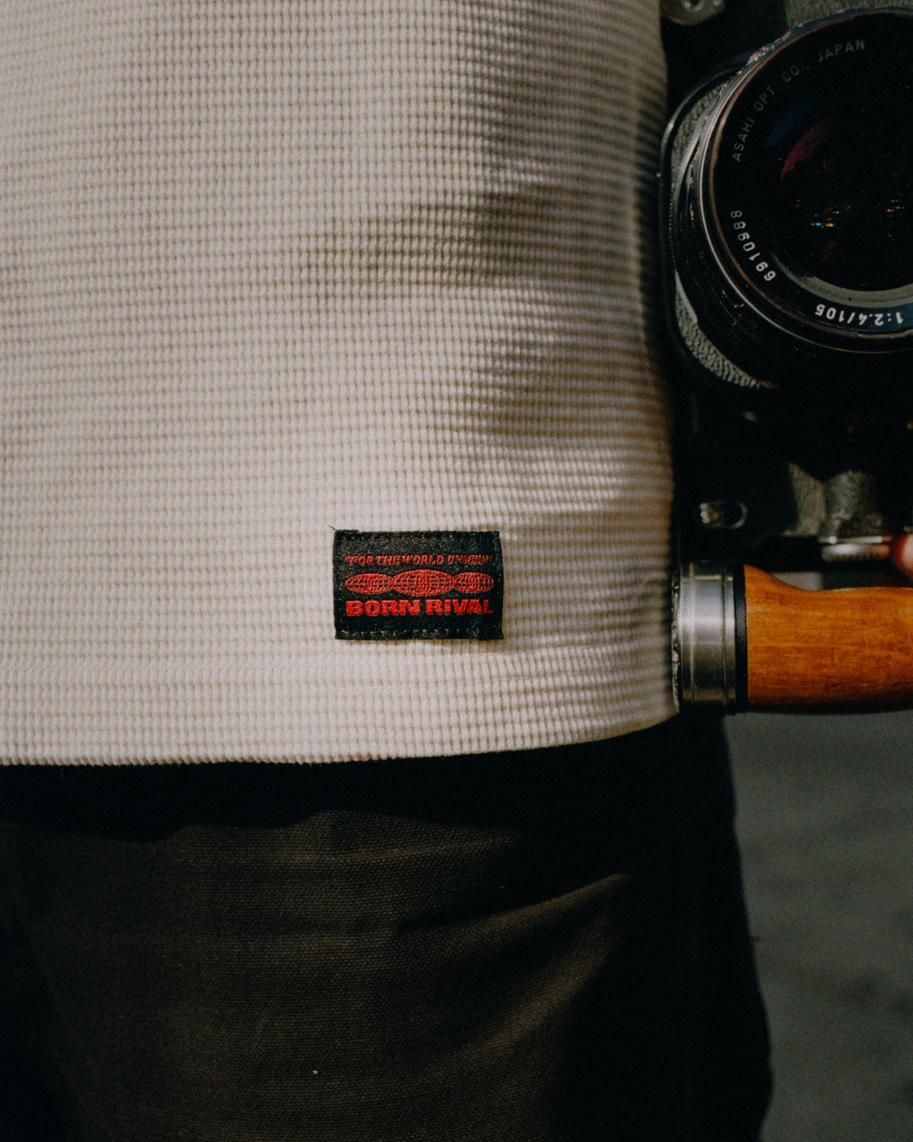 Person holding a camera with a visible brand label on clothing