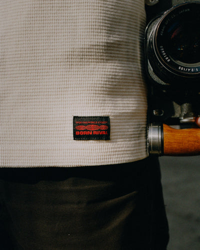 Person holding a camera with a visible brand label on clothing